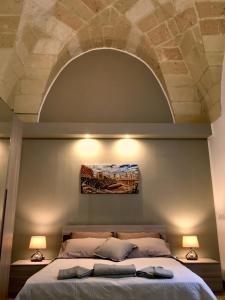 レッチェにあるWish Rooms Lecceのベッドルーム1室(ベッドの上にアーチ、ランプ2つ付)