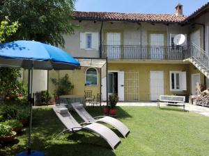 a yard with two lounge chairs and an umbrella at Casa Badinot in Diano dʼAlba