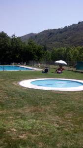 a person sitting under an umbrella next to a swimming pool at Casa Concejos in San Román de Cameros