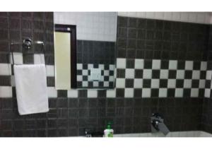 een badkamer met een dambordtegelwand en een wastafel bij Wonderful Stay At the Mall Road in Solan