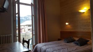 1 dormitorio con cama y ventana grande en Hôtel Restaurant Glaizette, en LʼArgentière-la-Bessée