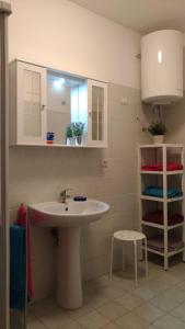 een badkamer met een wastafel, een spiegel en een kruk bij A casa di Lori in Catania