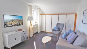 a living room with a couch and chairs and a tv at Westerstrasse Kajüten in Büsum