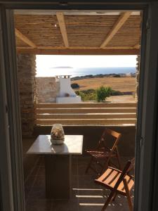 a patio with a table and a chair and a window at Ergina Summer Resort in Antiparos