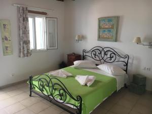 a bedroom with a bed with a green blanket at Ergina Summer Resort in Antiparos
