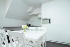 a white kitchen with a white table and chairs at Pantheon Palace By WP Hotels in Blankenberge