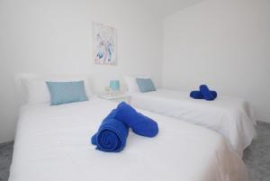 Dos camas blancas con toallas azules. en Calma Suites La Garita, en Arrieta