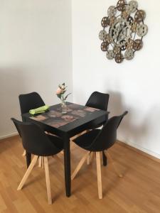 a black dining room table with black chairs and a chandelier at A&H Apartment in Oberhausen