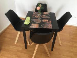 a black table with two chairs and a flower on it at A&H Apartment in Oberhausen