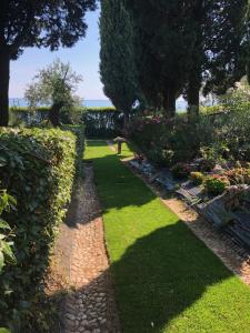 a garden with a bench and grass and trees at Appartamenti Villa Andrea in Garda