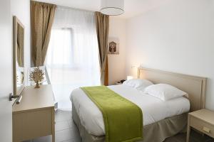 - une chambre avec un lit doté d'une couverture verte dans l'établissement Domitys Le Jardin Des Palmiers, à Ajaccio