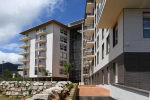 a row of tall buildings next to a stone wall at Domitys Le Jardin Des Palmiers in Ajaccio