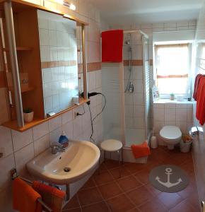 ein Bad mit einem Waschbecken, einer Dusche und einem WC in der Unterkunft Café Hausnordlicht - Ferienwohnung 1 in Dornum