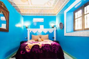 1 dormitorio con paredes azules y 1 cama con colcha púrpura. en Dar Berrada - Ziat, en Fez