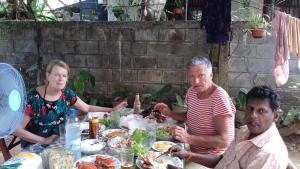 a group of people sitting around a table eating food at Prasad Suomi Villa in Matara