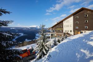 um comboio numa colina coberta de neve ao lado de um edifício em Hotel Emerich em Pec pod Sněžkou