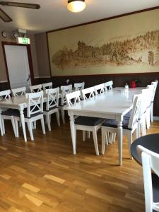 une salle à manger avec des tables et des chaises blanches dans l'établissement Hotell Björnidet, à Torsby