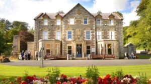 a large stone house with people standing in front of it at Teviot View Holiday Let’s Hawick in Hawick