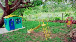 duas crianças brincam com equipamento num quintal ao lado de uma árvore em Pousada Portalcion em Goiás