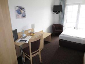 a hotel room with a bed and a desk and a bed and a bedskirts at Wein & Gästehaus Rosenlay in Lieser