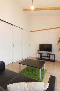 een woonkamer met een tafel en een flatscreen-tv bij Guesthouse Tokushima in Tokushima