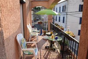 a balcony with chairs and a table with an umbrella at Estagel in Estagel