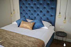 a bed with a blue headboard and pillows on it at Three Pearls Deluxe Rooms & Studios in Zadar