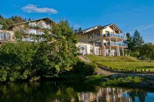 ein großes Haus auf einem Hügel neben einem Fluss in der Unterkunft Naturhotel Rebling in Bernried