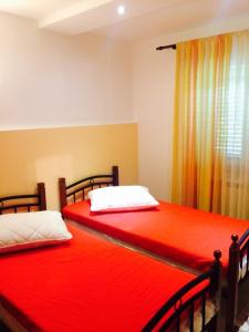 two beds in a room with red sheets and a window at Apartman Lovor in Medulin