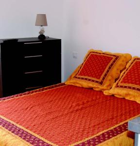- une chambre avec un lit doté d'oreillers orange et rouge dans l'établissement La goutte d'or, à Roussillon