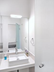 Baño blanco con lavabo y espejo en Brand new budget apartment next to Iaso and Oaka, en Atenas