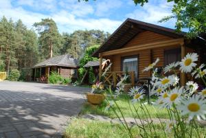 a log cabin with flowers in front of it at Audrones sodyba in Šventoji