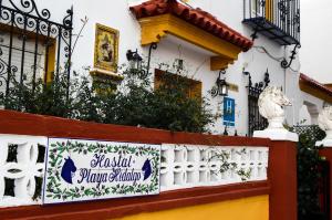 a building with a sign on a fence at Hostal Playa Hidalgo in Rota