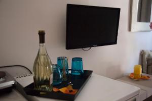 a bottle of wine on a tray with glasses and a television at Angelika in Áyios Andréas Messinias