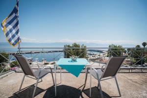 a table and chairs on a balcony with a view of the water at Angelika in Agios Andreas