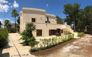 una casa blanca con una palmera delante de ella en B. & B. Lu Turnitu, en Maruggio