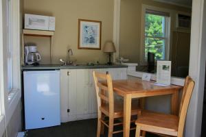 a small kitchen with a wooden table and a refrigerator at Kennebunk Gallery Motel and Cottages in Kennebunk