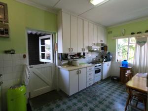a kitchen with green walls and white cabinets at Leo's Den in Fish hoek