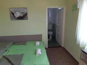a bedroom with a green bed with slippers on it at Király Apartman in Fonyód