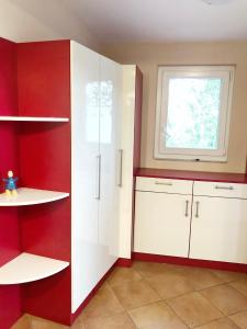 a kitchen with red and white cabinets and a window at Villa Masha in Omišalj