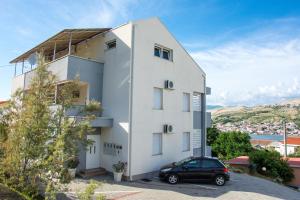 a black car parked in front of a white building at Apartments Sv. Jelena 2 in Pag