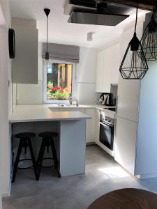 a kitchen with white cabinets and a kitchen island with stools at Pokoje Gościnne Parkowa 2 in Świeradów-Zdrój