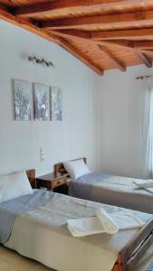 two beds in a white room with wooden ceilings at Villa Maraki in Agia Paraskevi