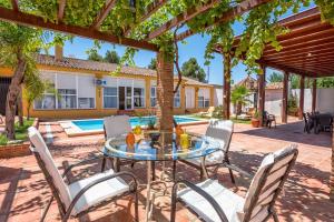 un patio con mesa de cristal y sillas en La torre Casa rural en Fuente de Piedra