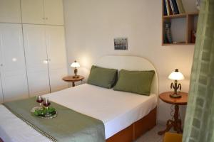 Mayra Apartment في Lithakia: غرفة نوم مع سرير وطاولتين مع أكواب من النبيذ