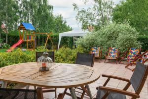 a wooden table with chairs and a playground at FOR YOU dom dla 10 osób in Białogóra