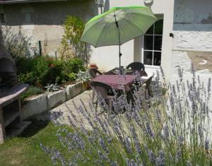 a table with a green umbrella in a garden at Gite Chambres d Hotes des Péguets in Faverolles