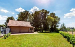 a wooden cabin in a field with a fence at Csendliget Villas Abádszalók in Abádszalók