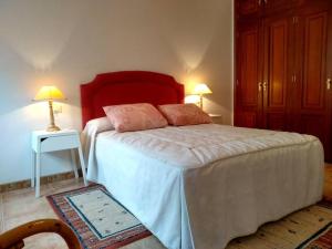 a bedroom with a bed with a red headboard and two lamps at Pilar Villanueva in Bueu