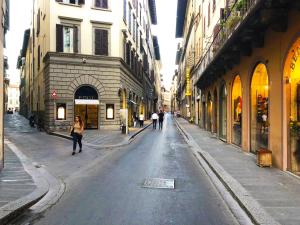 a woman walking down a city street with buildings at Florentine Style Central Apartments in Florence